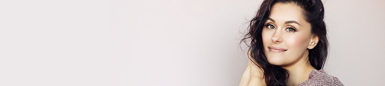 Smiling woman with dark hair in soft lighting.