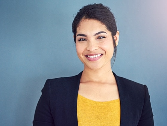 Smiling woman in professional attire against blue background.