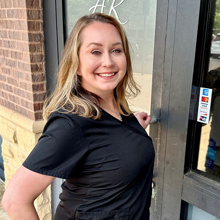 Woman smiling by a shop entrance.