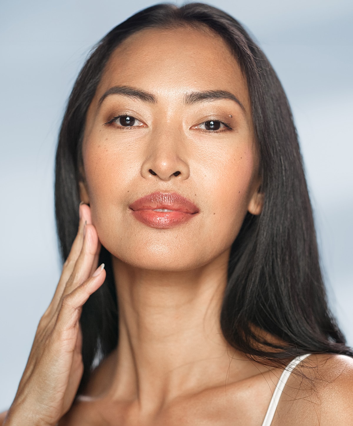 Woman with long hair touching her face.