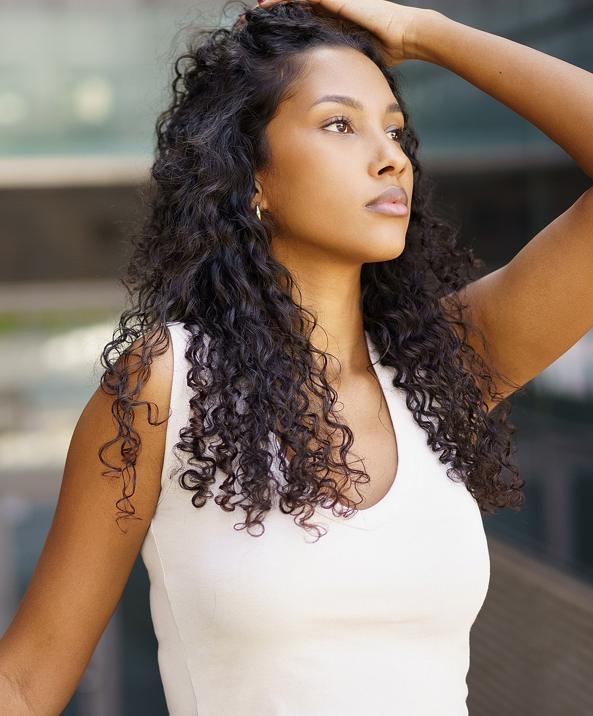 Young woman with curly hair in thoughtful pose.