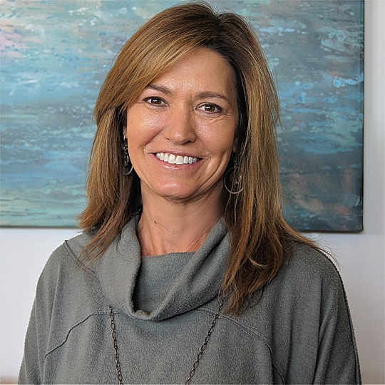 Smiling woman in a gray sweater.