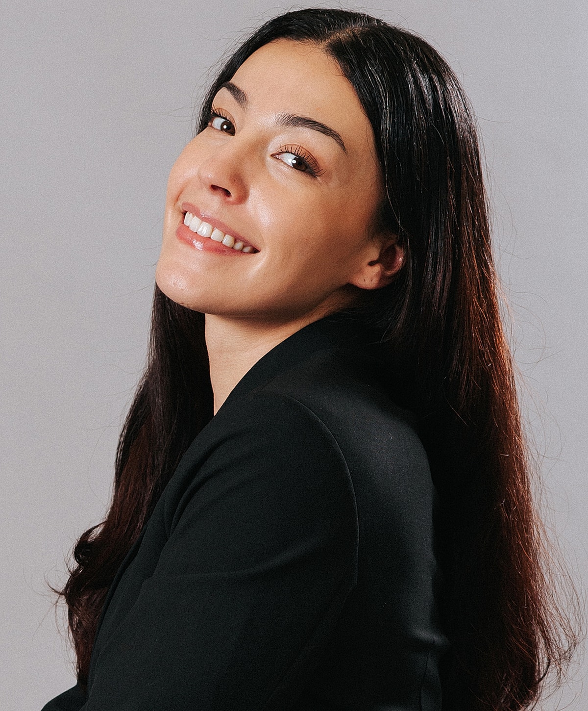 Smiling woman with long, dark hair against gray.