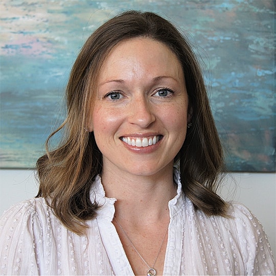Smiling woman with wavy hair, white blouse.