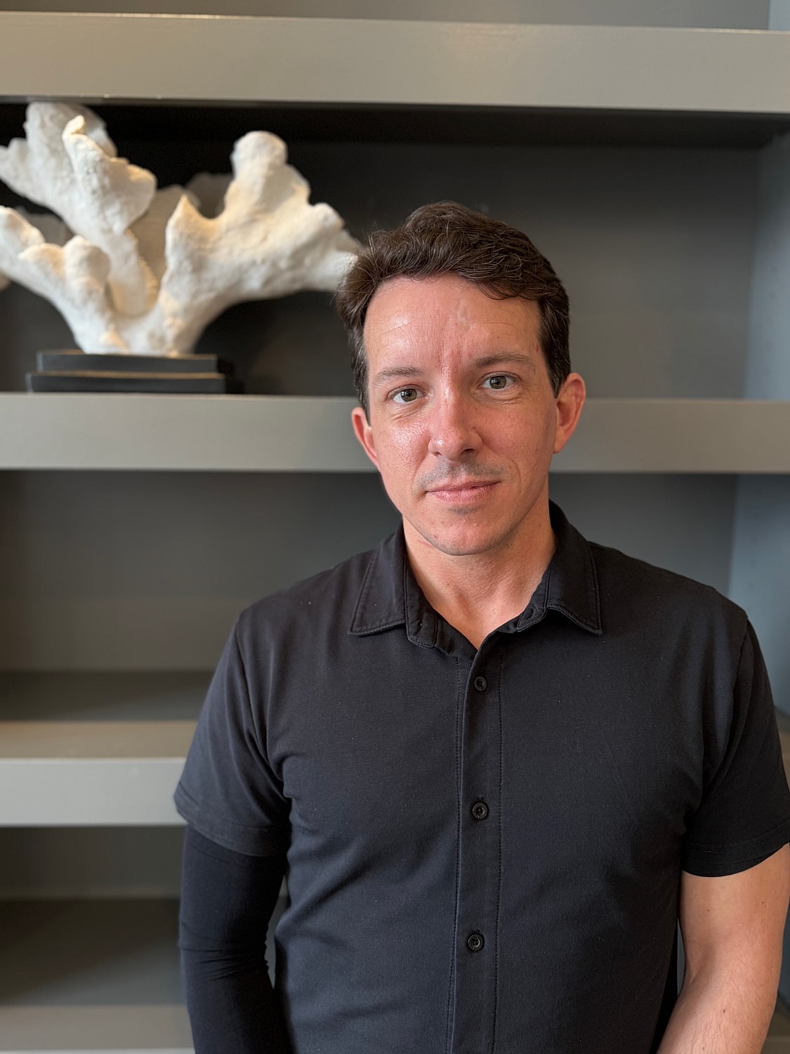 Person in a black shirt, coral sculpture backdrop.