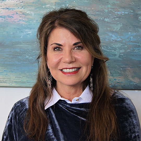 Smiling woman with long hair and earrings.
