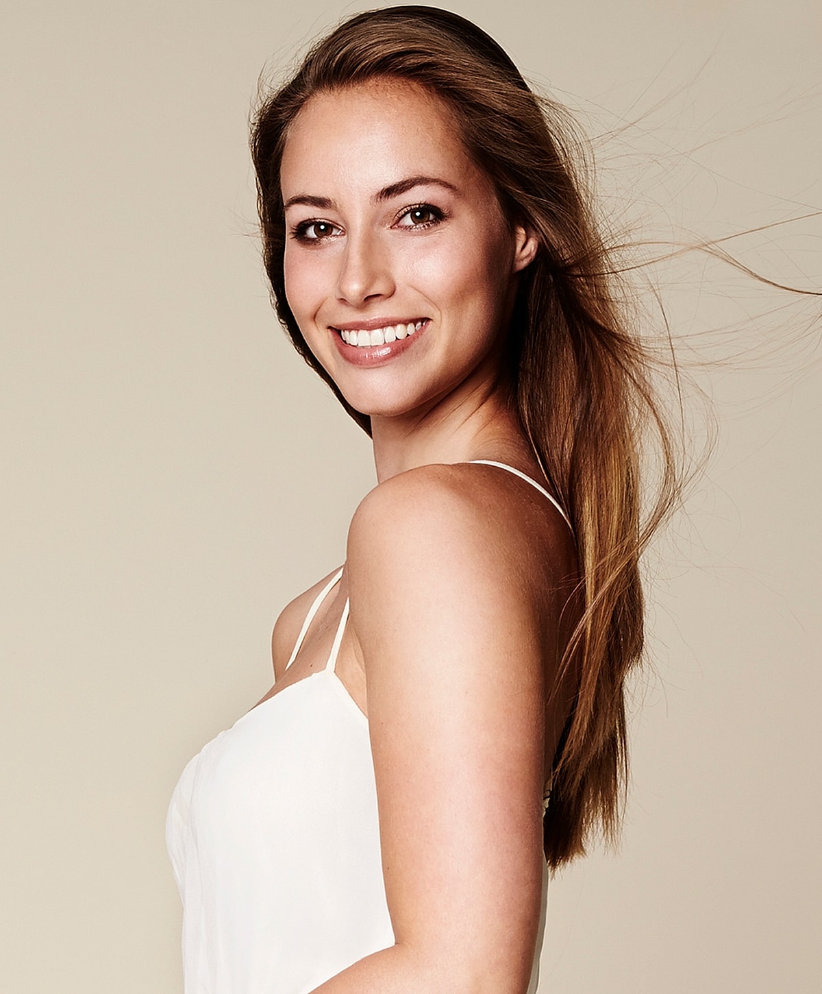 Smiling woman with long hair in white dress.