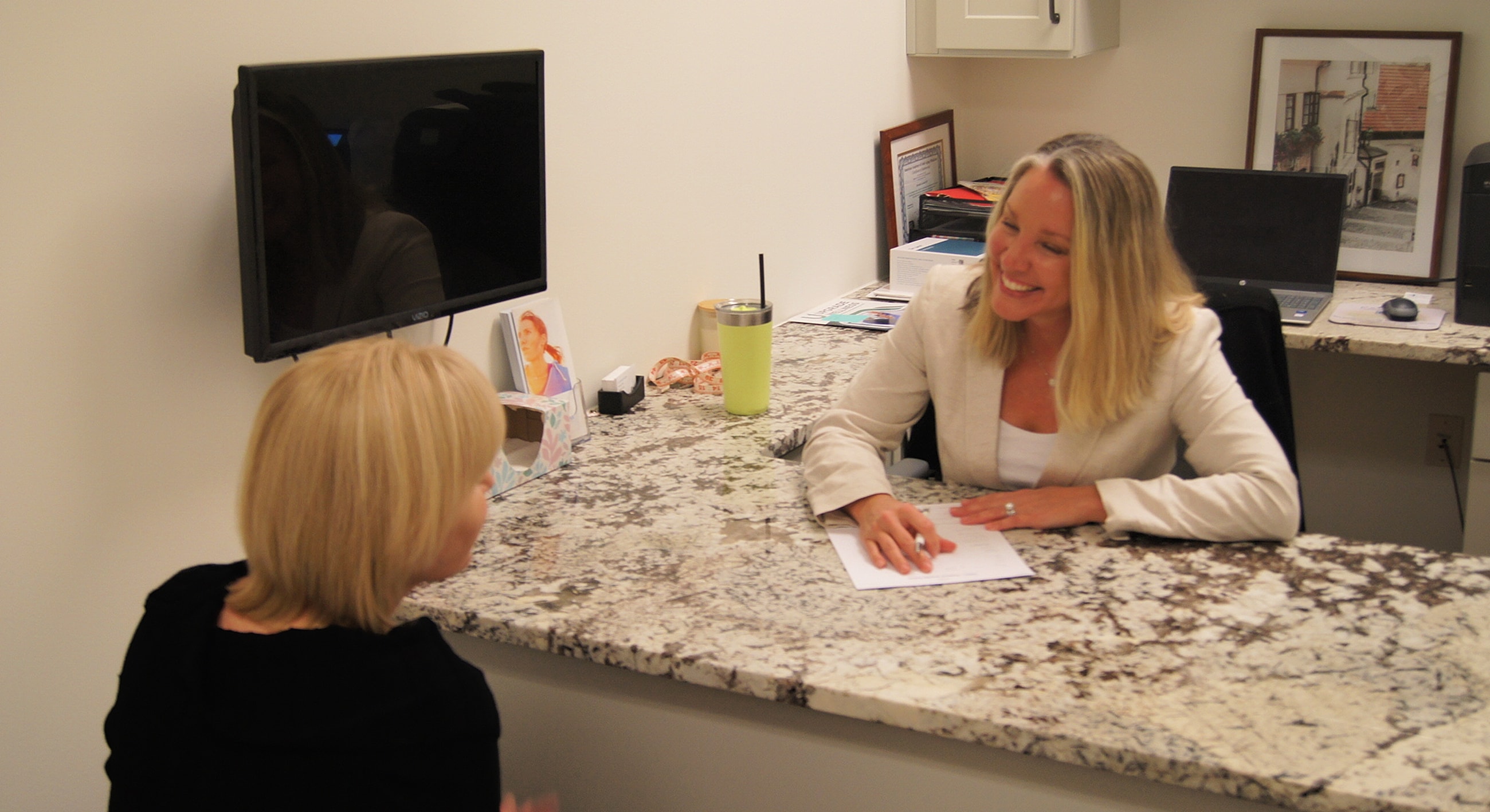 Two women engaged in conversation at a desk.