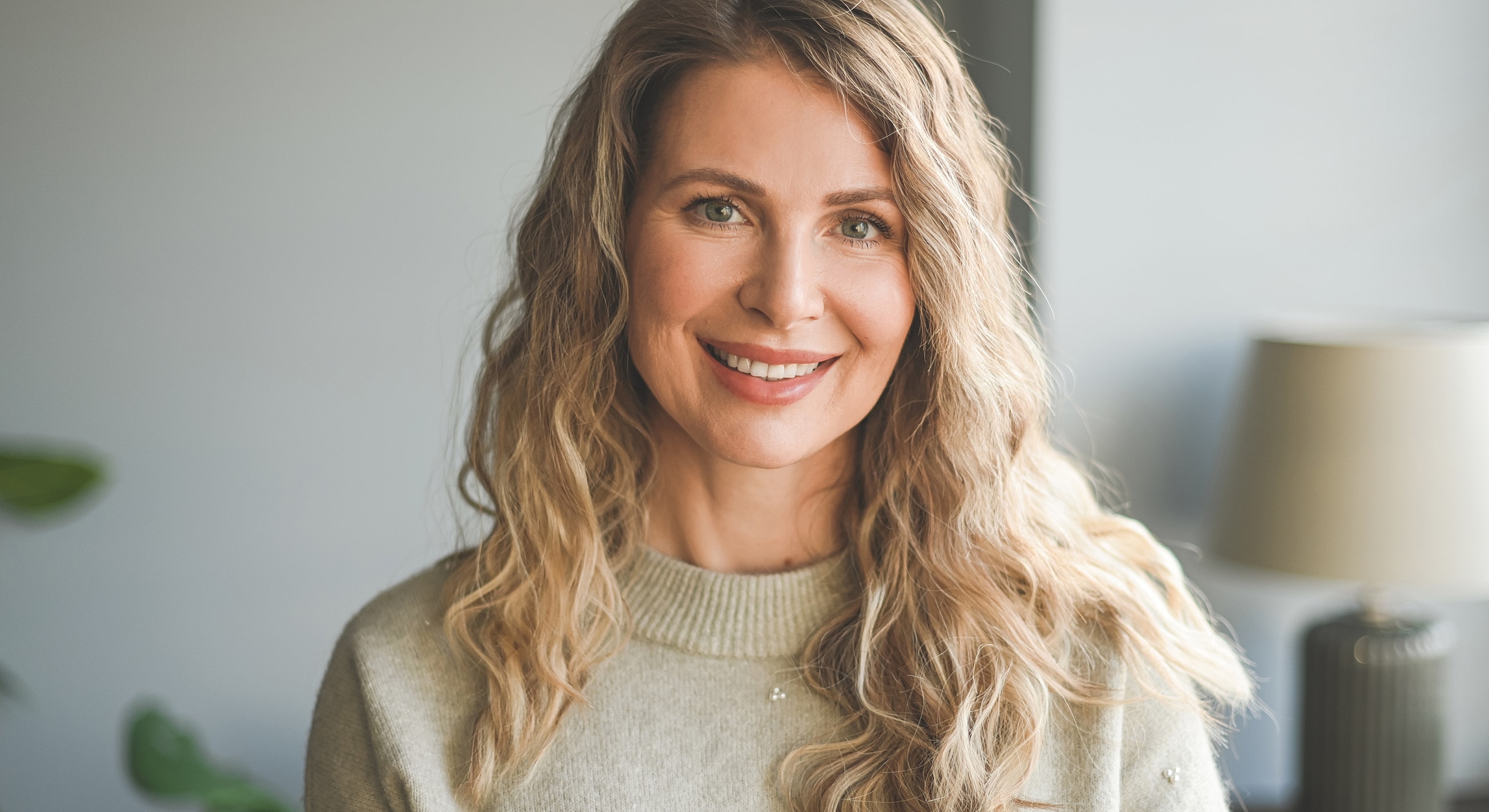 Smiling woman with wavy hair indoors.