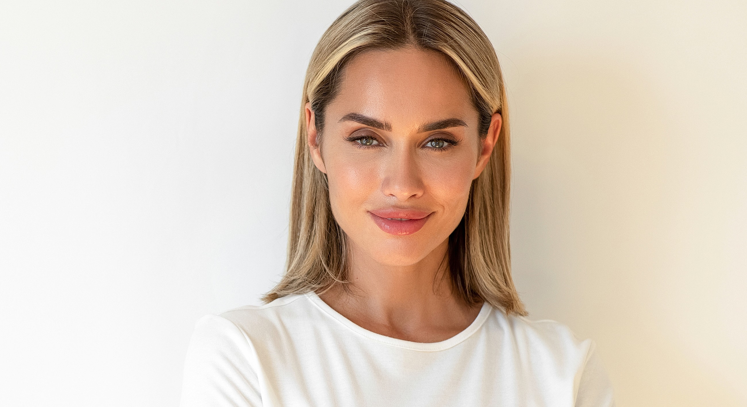 Smiling woman with blonde hair on neutral background