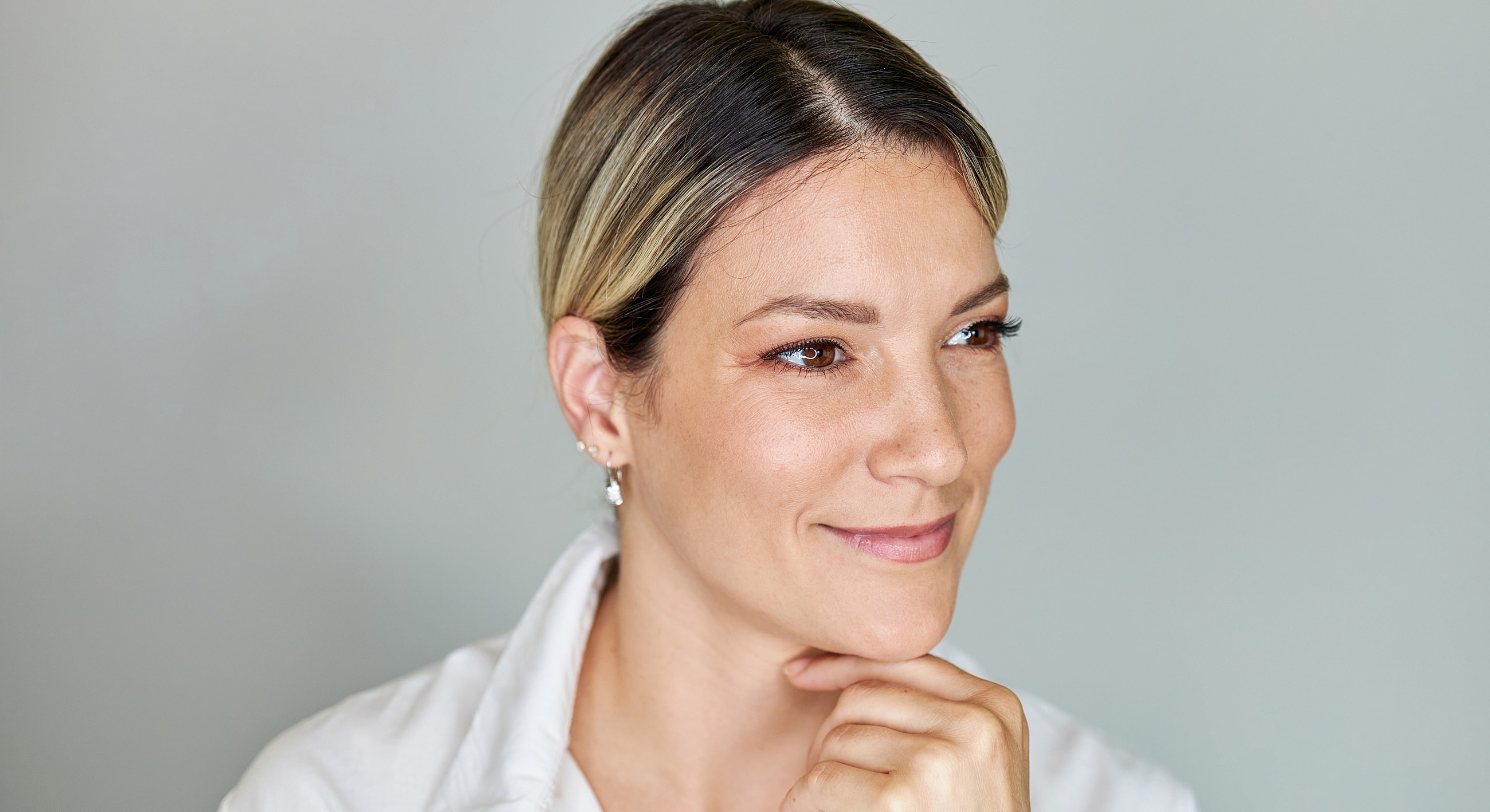 Smiling woman with hand on chin.